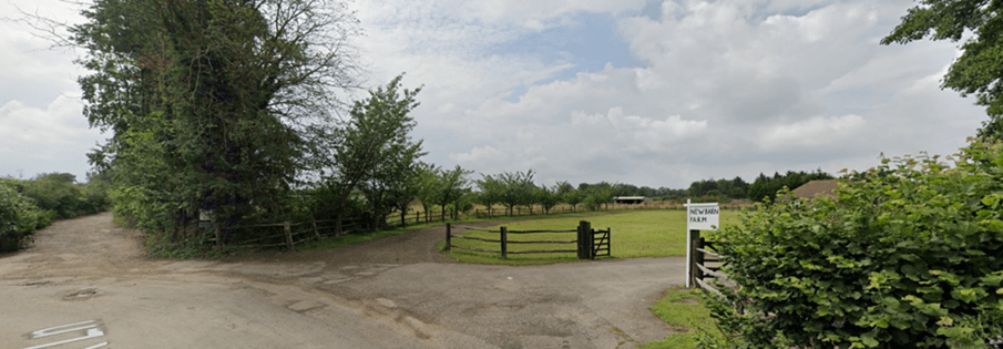 A rural lane with low level open timber fencing painted black, formed of upright posts